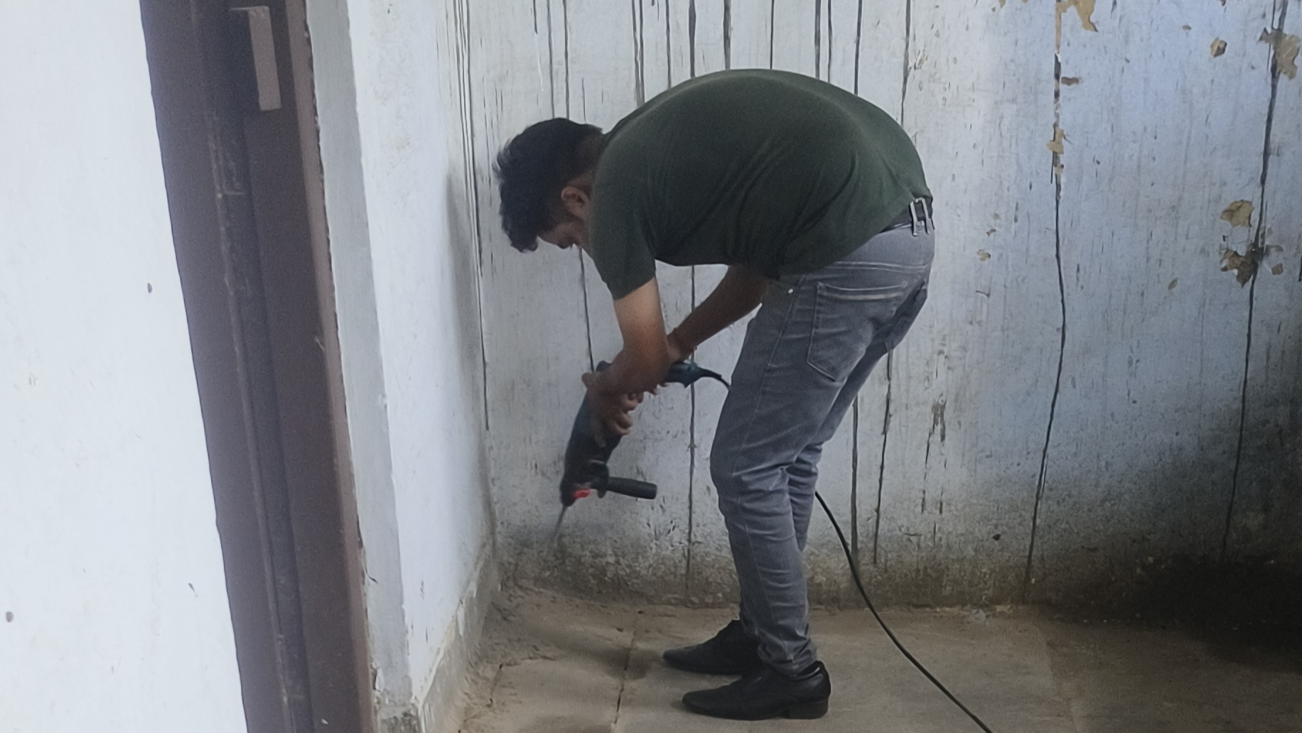 Technician drilling wall for termite treatment in Jankipuram home